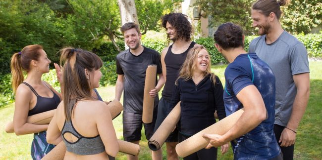 Cheerful people with yoga mats chatting and laughing